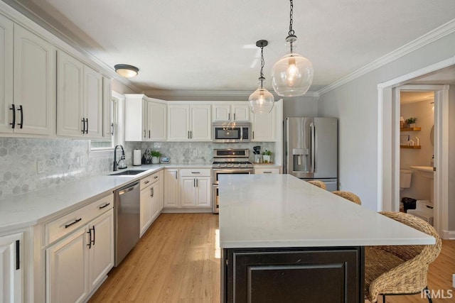 3154 Sand Walk Dr, Kokomo, IN 46902 - kitchen with stainless steel appliances, a sink, a kitchen island, light wood-type flooring, and white cabinets