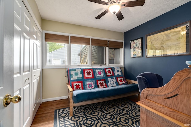 sitting room with a textured ceiling, baseboards, wood finished floors, and ceiling fan