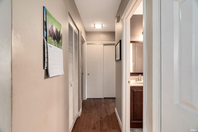 corridor featuring dark wood finished floors and a sink