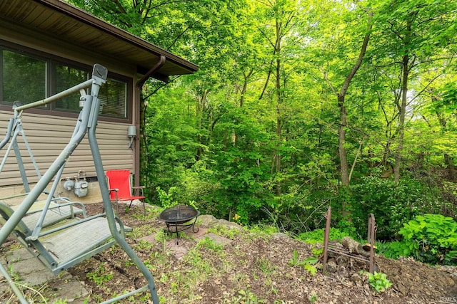 view of yard with a fire pit and a wooded view