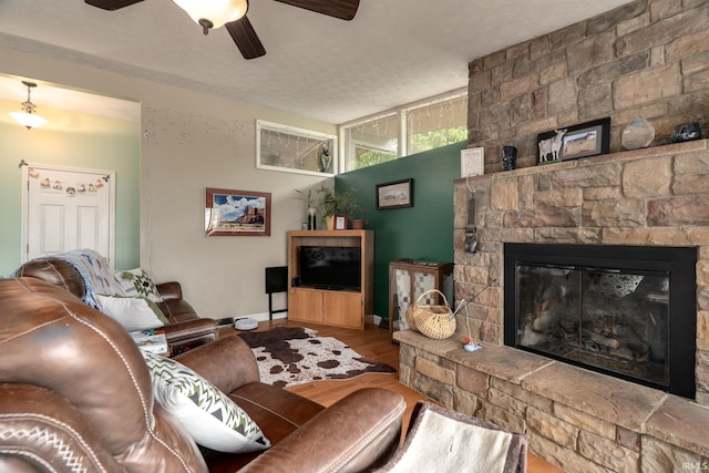 living area with a fireplace, a ceiling fan, wood finished floors, and baseboards
