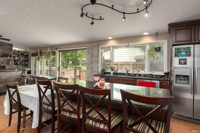 dining space with a textured ceiling, light wood-type flooring, and vaulted ceiling