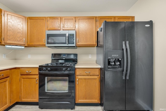kitchen featuring black appliances, light wood-type flooring, and light countertops