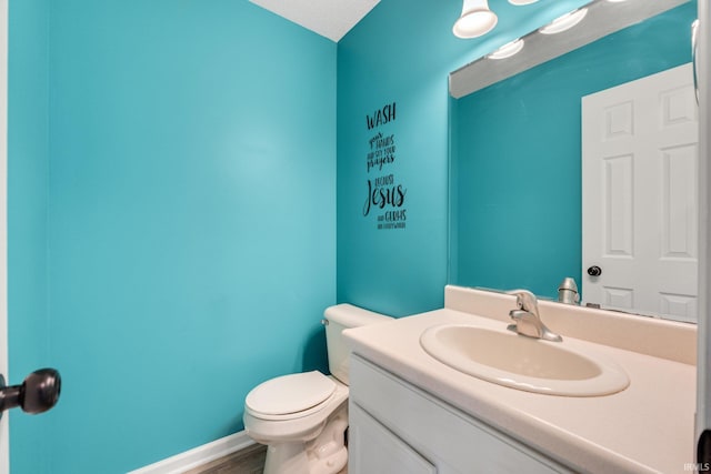 half bath featuring vanity, toilet, wood finished floors, and baseboards