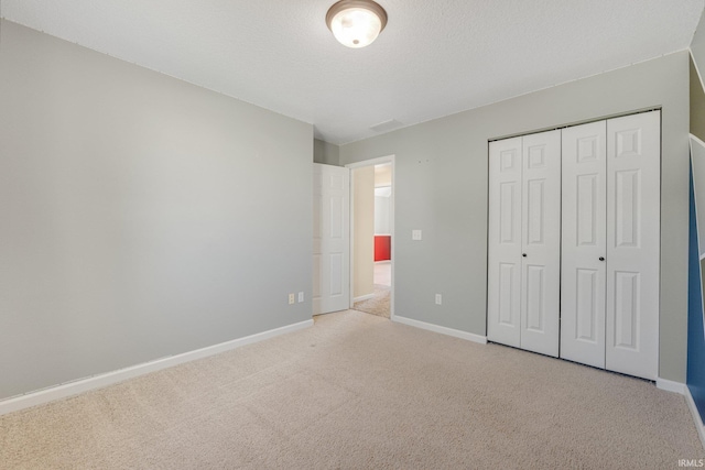 unfurnished bedroom featuring light colored carpet, baseboards, and a closet