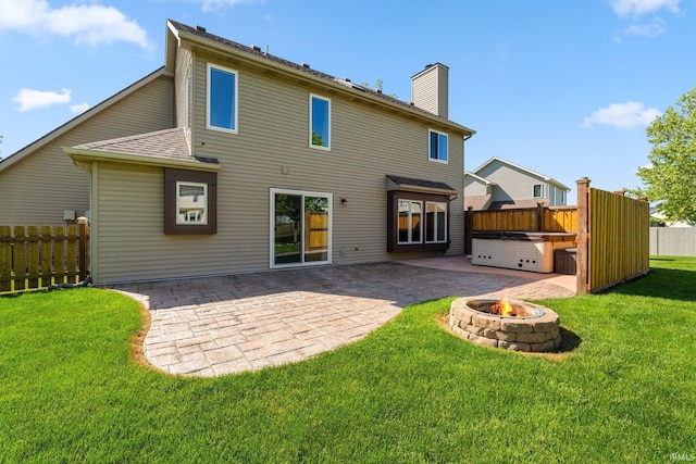 rear view of property with an outdoor fire pit, a patio, a chimney, and a hot tub