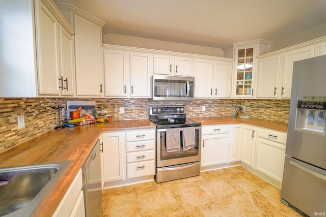 2027 Wesmar Ct, Kokomo, IN 46902 - kitchen with appliances with stainless steel finishes, backsplash, butcher block counters, and glass insert cabinets