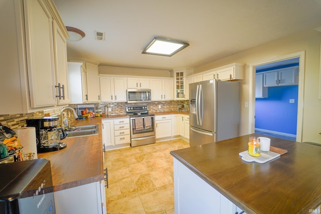 2027 Wesmar Ct, Kokomo, IN 46902 - kitchen with appliances with stainless steel finishes, a sink, backsplash, and glass insert cabinets