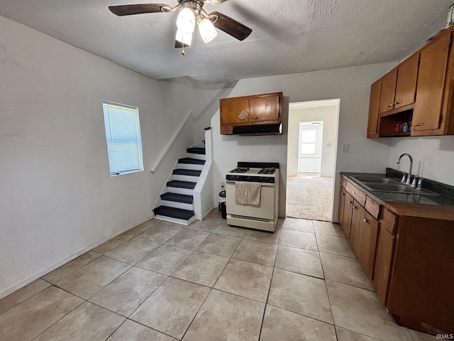 721 S Hackley St, Muncie, IN 47302 - kitchen featuring white range with gas cooktop, a sink, dark countertops, under cabinet range hood, and brown cabinets