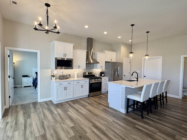 kitchen featuring appliances with stainless steel finishes, wall chimney exhaust hood, dark wood-style flooring, a sink, and recessed lighting