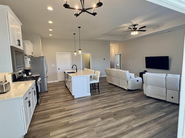 kitchen featuring appliances with stainless steel finishes, open floor plan, dark wood-type flooring, a kitchen breakfast bar, and recessed lighting