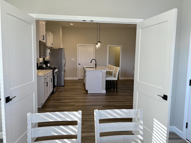kitchen with appliances with stainless steel finishes, a breakfast bar area, baseboards, dark wood-style floors, and light countertops