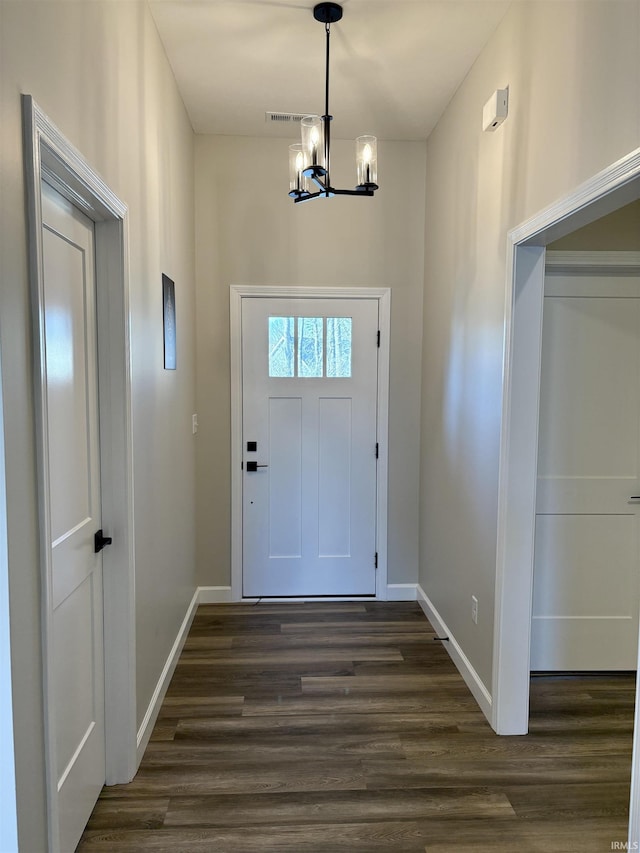 foyer entrance featuring a chandelier, baseboards, and dark wood-type flooring