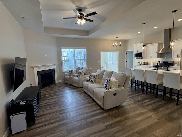 living area featuring dark wood-style floors, a ceiling fan, a high end fireplace, a chandelier, and baseboards