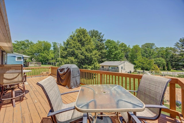4110 E 10th St, Bloomington, IN 47408 - wooden deck with outdoor dining space, a grill, and view of scattered trees