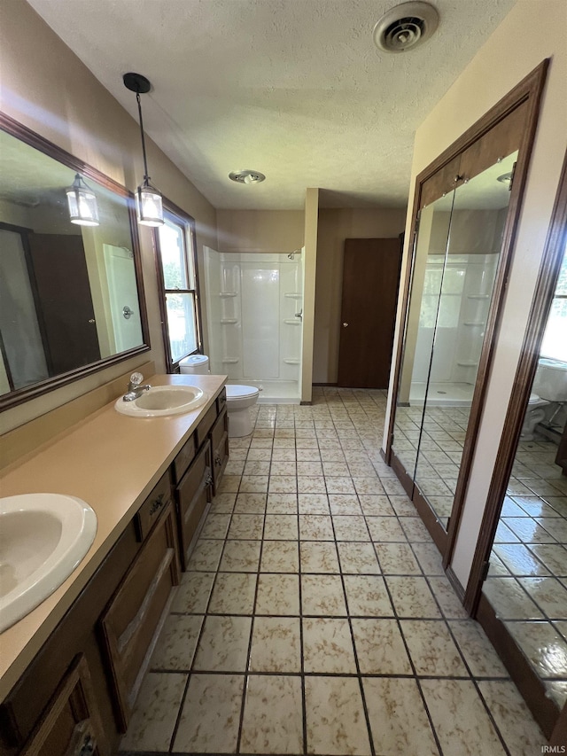 3613 Robin Dr, Kokomo, IN 46902 - bathroom featuring a textured ceiling, a stall shower, toilet, and double vanity