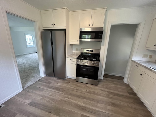 3534 Oakcrest Dr, South Bend, IN 46615 - kitchen featuring stainless steel appliances, white cabinets, light wood-type flooring, and baseboards
