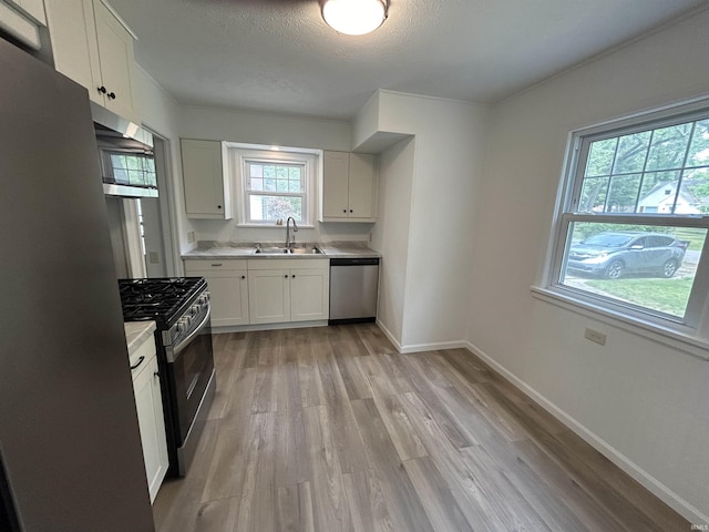 3534 Oakcrest Dr, South Bend, IN 46615 - kitchen with appliances with stainless steel finishes, a sink, light wood finished floors, light countertops, and white cabinetry