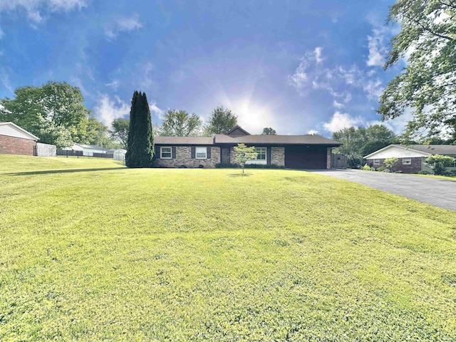 single story home featuring driveway, a carport, a front lawn, and stone siding