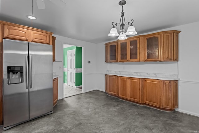 kitchen with stainless steel fridge, brown cabinets, glass insert cabinets, decorative light fixtures, and ceiling fan