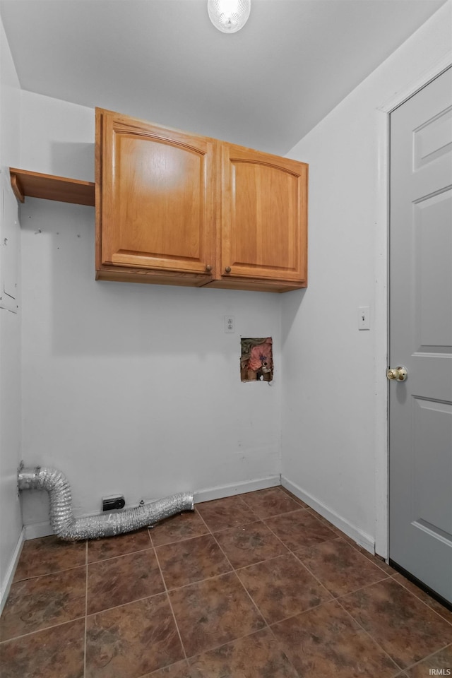 washroom featuring cabinet space, baseboards, washer hookup, and dark tile patterned flooring