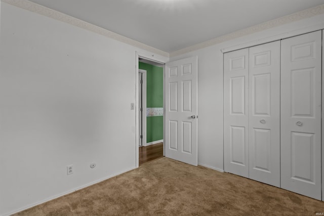 unfurnished bedroom with carpet floors, a closet, and baseboards