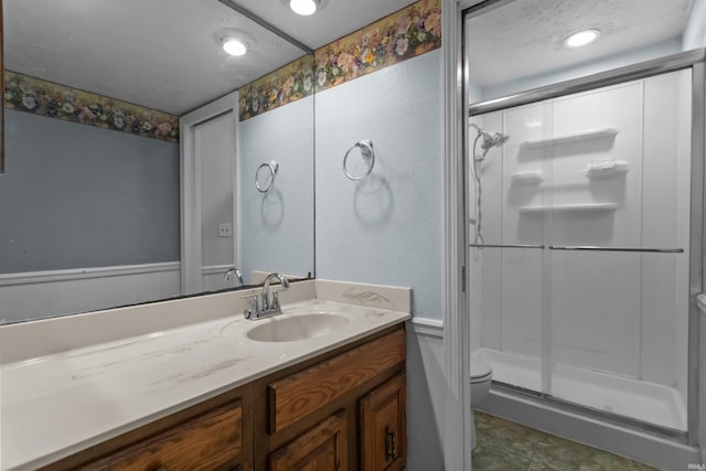 bathroom with toilet, a stall shower, and vanity