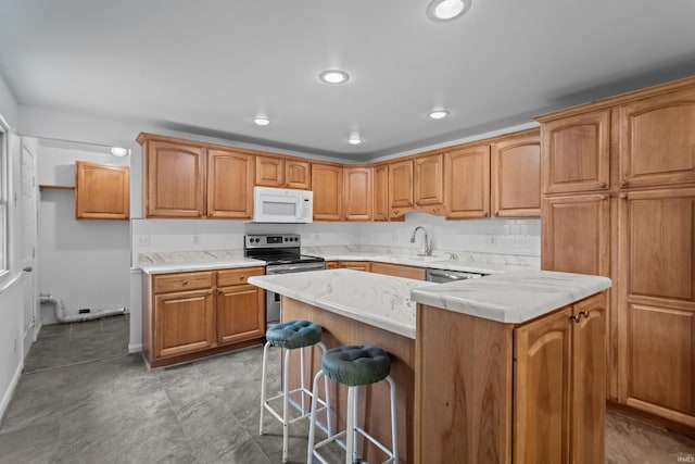 kitchen with white microwave, stainless steel electric range, a kitchen bar, a sink, and a center island