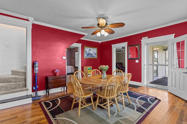 dining room with a ceiling fan, stairway, hardwood / wood-style floors, ornamental molding, and baseboards