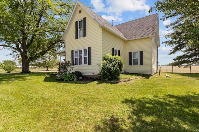 rear view of house with a yard and a shingled roof