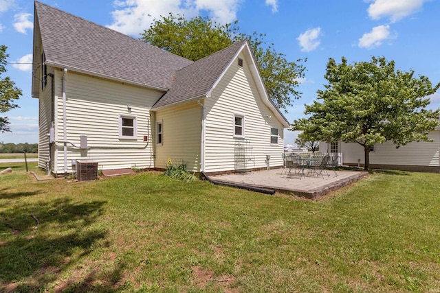 rear view of property with roof with shingles, a patio, a lawn, and central AC unit
