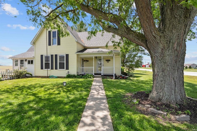 view of front of house with a porch, roof with shingles, and a front lawn