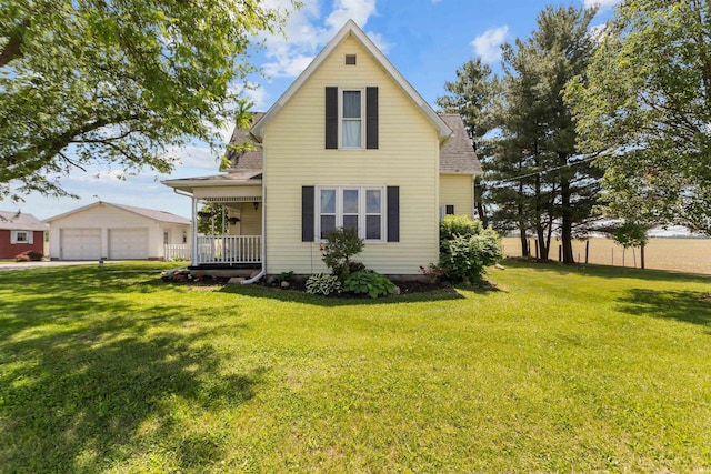 back of house featuring covered porch, a lawn, a detached garage, and a shingled roof