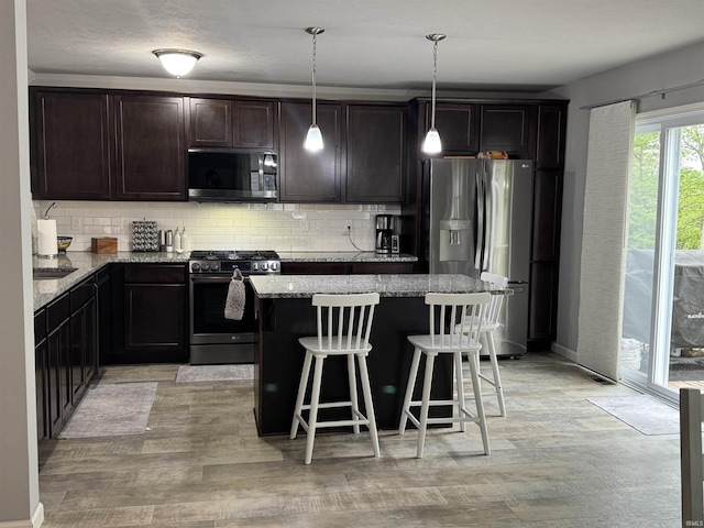 716 Gentry Ln, New Carlisle, IN 46552 - kitchen featuring stainless steel appliances, a kitchen island, decorative backsplash, and dark brown cabinetry