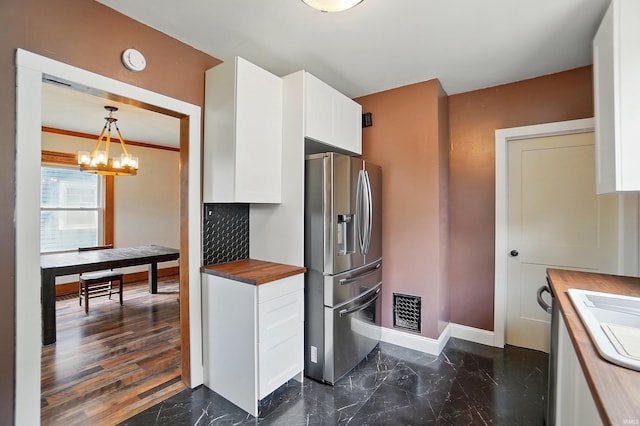 kitchen featuring stainless steel fridge, butcher block counters, baseboards, white cabinets, and a chandelier