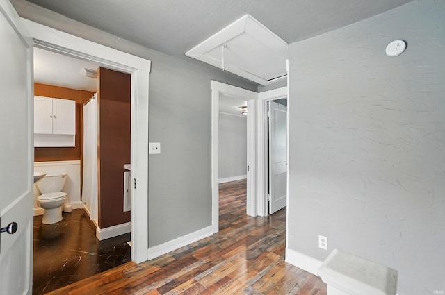corridor featuring attic access, baseboards, and hardwood / wood-style flooring