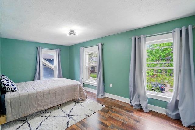 bedroom with baseboards, wood finished floors, and a textured ceiling
