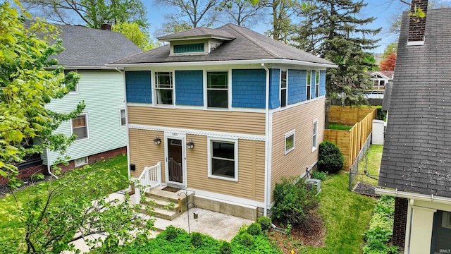 view of front of home with fence, central air condition unit, and roof with shingles