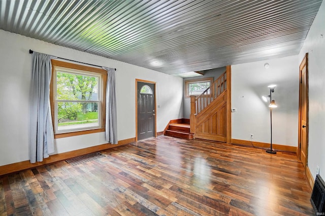 unfurnished living room with stairs, wood-type flooring, and baseboards