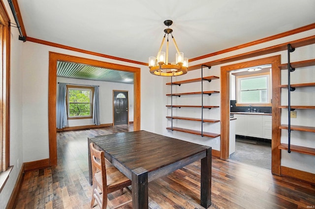 dining space with a chandelier, ornamental molding, dark wood-type flooring, and baseboards
