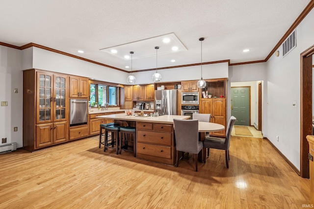 13392 N State Road 13, North Manchester, IN 46962 - kitchen with appliances with stainless steel finishes, brown cabinetry, light wood-style flooring, a kitchen bar, and a spacious island