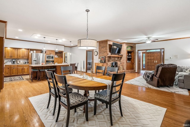 13392 N State Road 13, North Manchester, IN 46962 - dining area with light wood finished floors, ceiling fan, crown molding, a brick fireplace, and recessed lighting