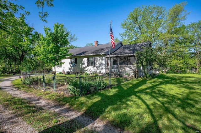 rear view of house with a sunroom, a chimney, and roof with shingles