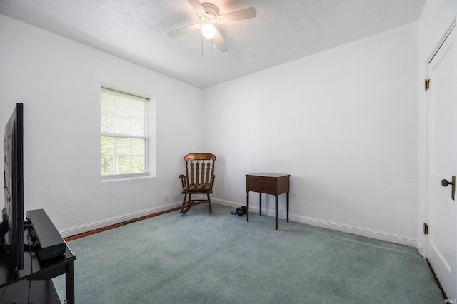 sitting room featuring carpet floors, a ceiling fan, baseboards, and a textured ceiling