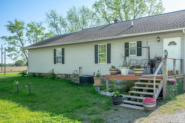 back of house featuring a lawn, central air condition unit, and a shingled roof