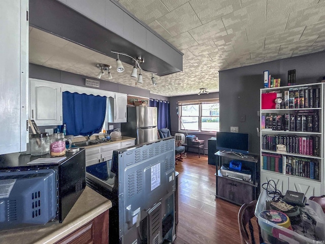 315 W Butcher St, Geneva, IN 46740 - kitchen with freestanding refrigerator, dark wood-type flooring, white cabinetry, light countertops, and a sink