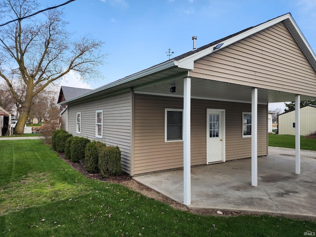 back of property with a lawn, a patio, and a carport