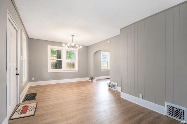 1614 Kendall St, South Bend, IN 46613 - unfurnished dining area featuring arched walkways, wood finished floors, a chandelier, baseboards, and a textured ceiling