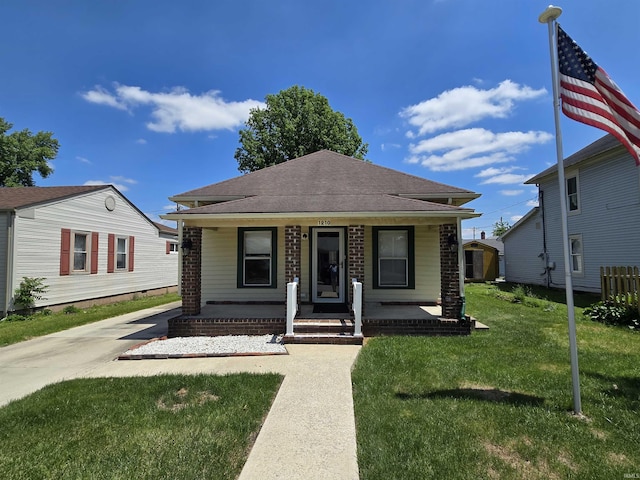 view of front of home featuring a front yard, a porch, and a shingled roof