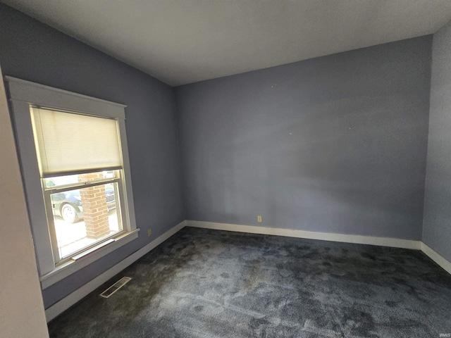 spare room with dark carpet and baseboards